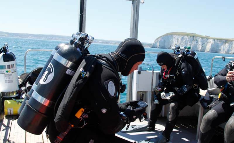 Image of scuba divers with air cylinders on a boat